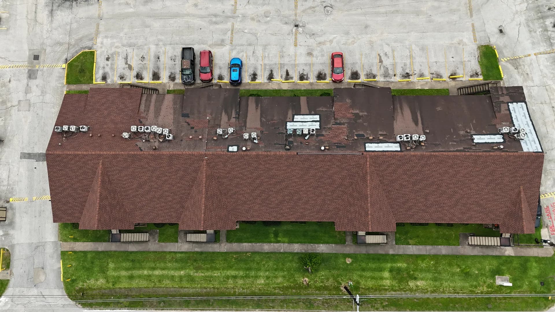 Aerial view of a multi-building apartment community with pitched shingle roofs over occupied units