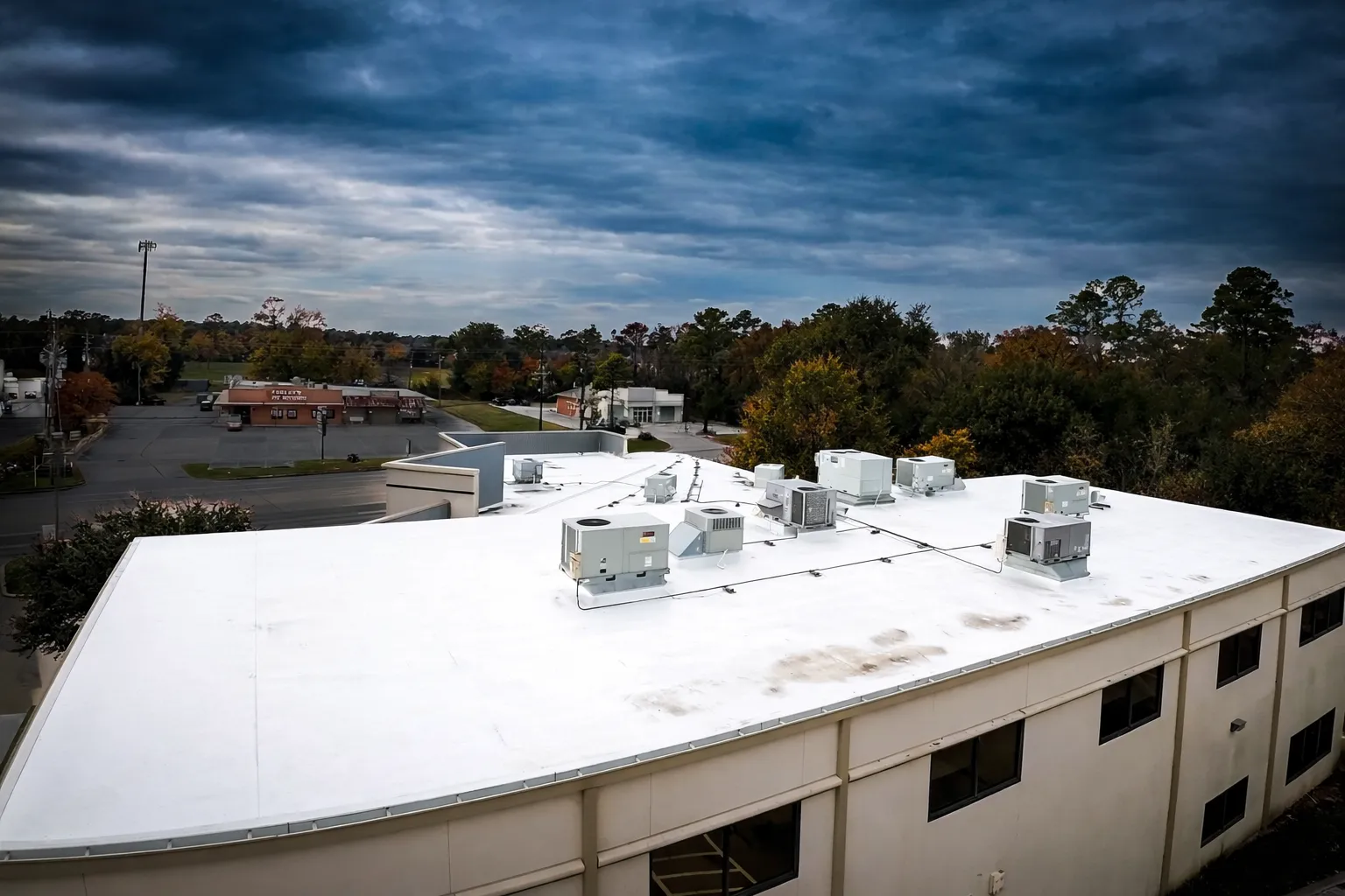 Aerial view of a white single ply membrane roof on a commercial bank branch, the low-slope category EPDM competes in