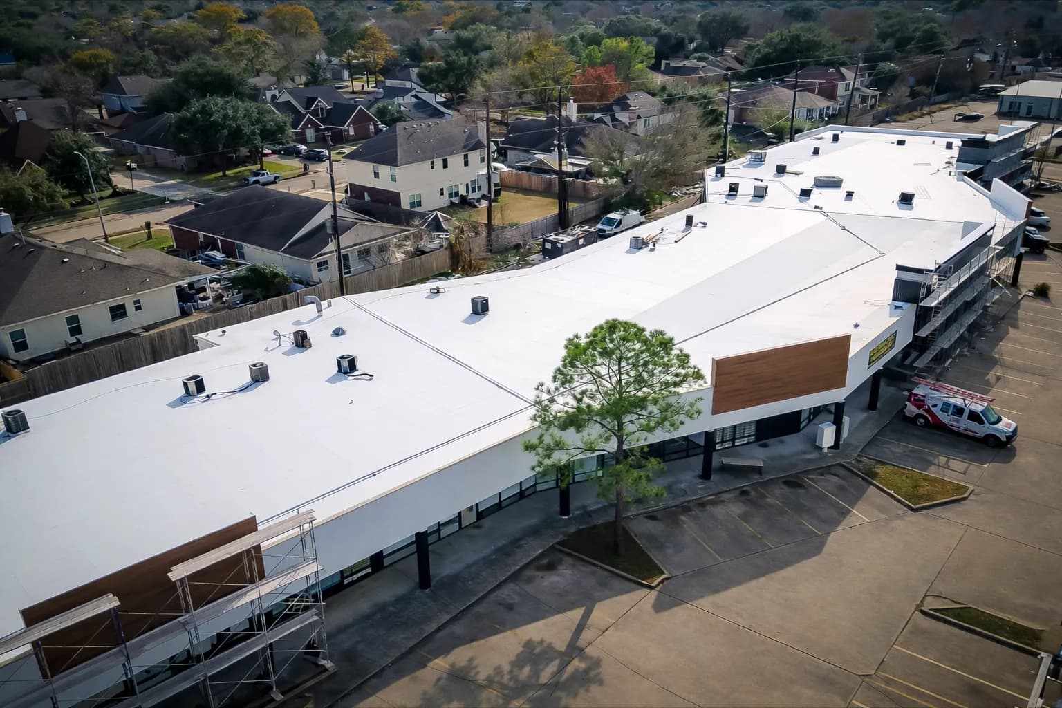 Aerial view of a large commercial TPO roof membrane with multiple rooftop HVAC units and equipment curbs