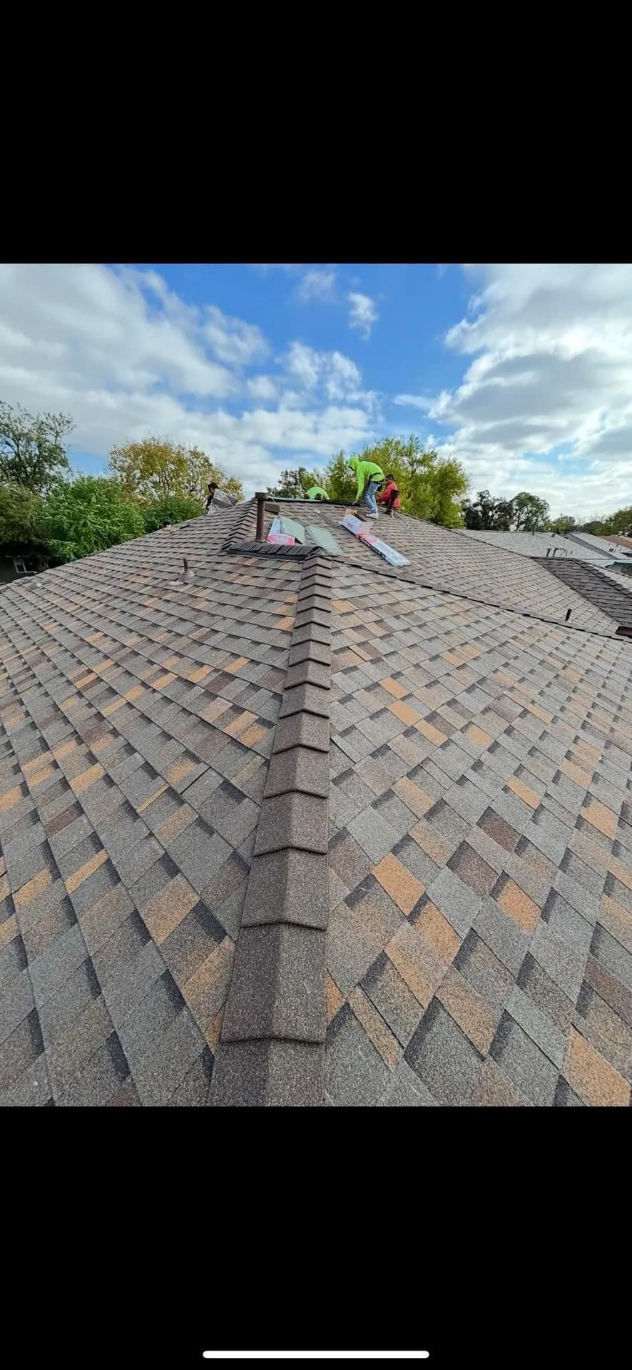 Closeup of two ROYH Build Co roofers installing ridge cap shingles along the peak of a shingle roof