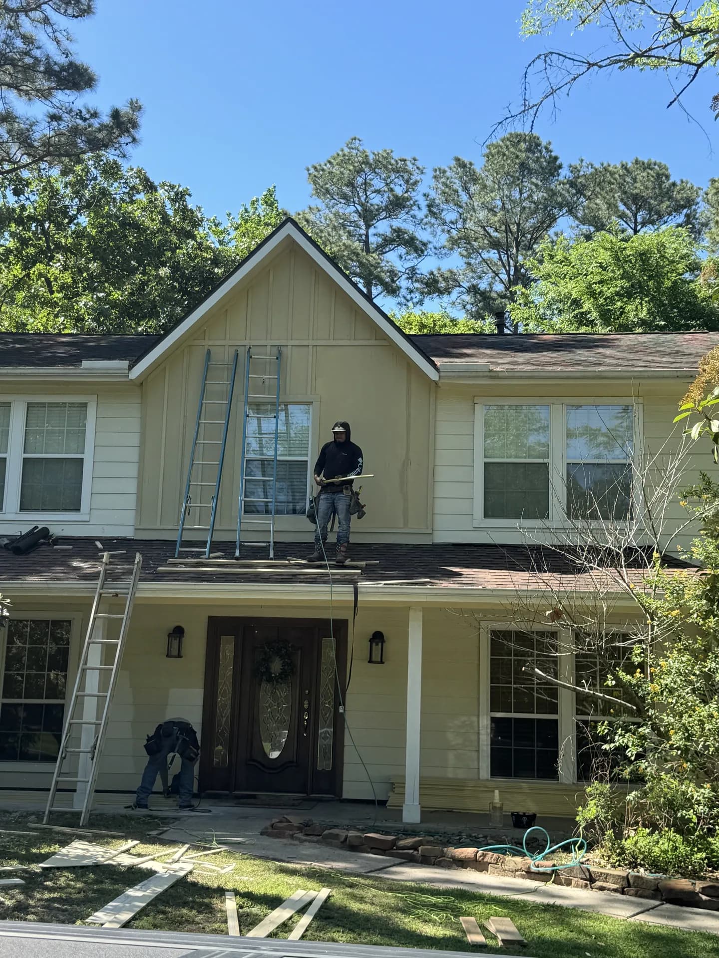 ROYH Build Co crew member working near the front gable of a two-story home with ladders in place