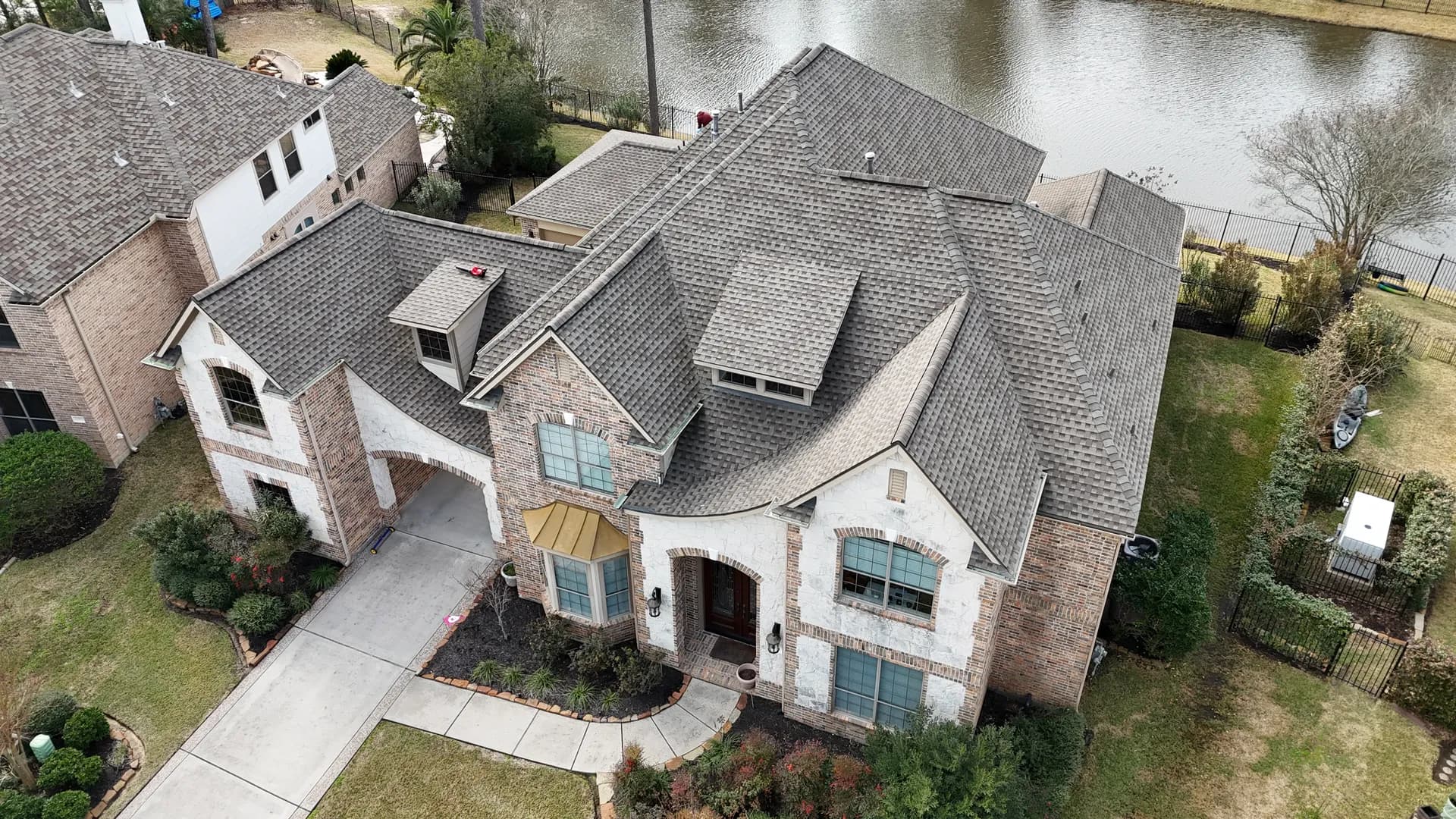 Aerial view of a dimensional shingle roof with a staggered, shake-style profile on a lakefront home near The Woodlands, TX