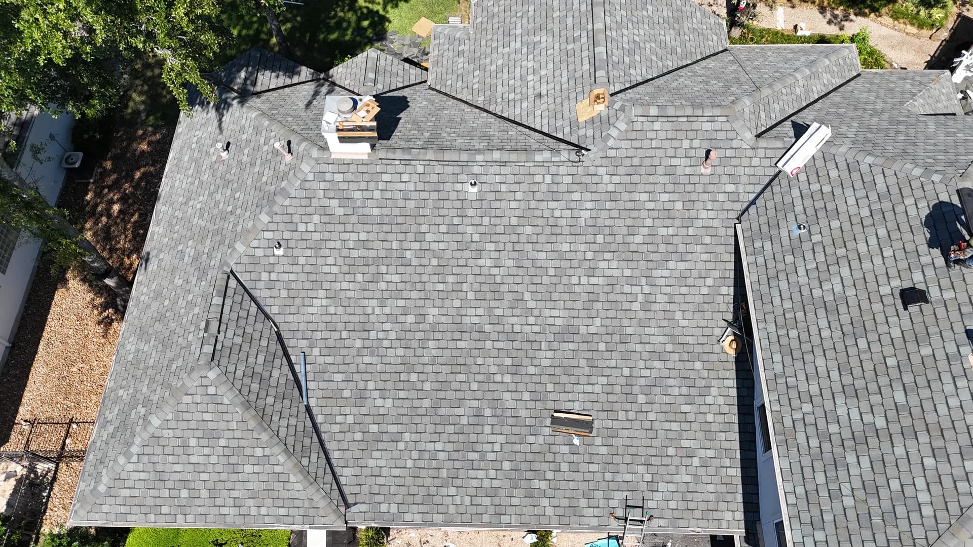 Aerial view of a gray dimensional shingle roof near The Woodlands, TX, the type of roof plane where a MrCool solar attic fan is mounted and flashed