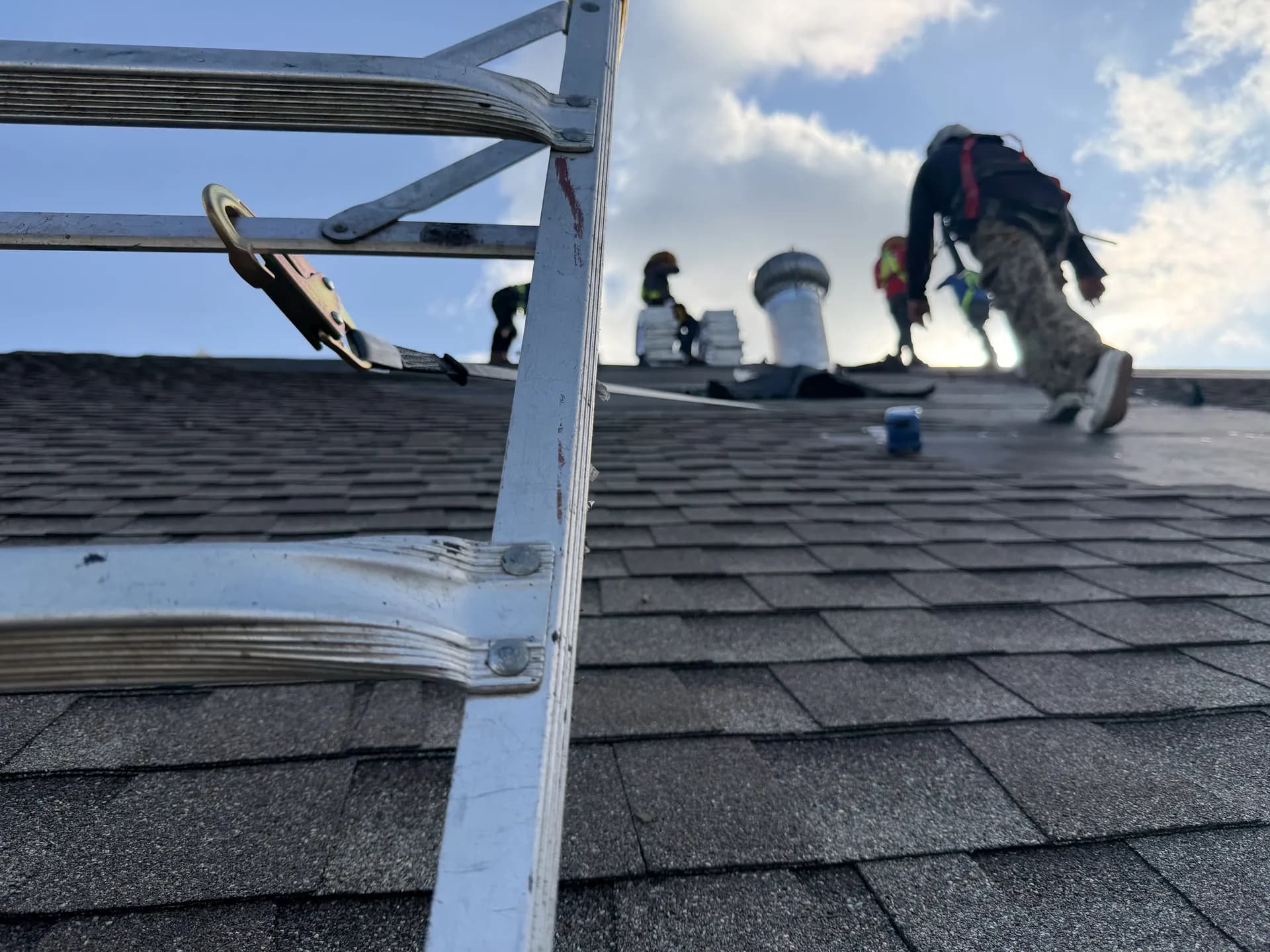 Silhouette of a ROYH Build Co roofing crew working along a roof ridge at dusk