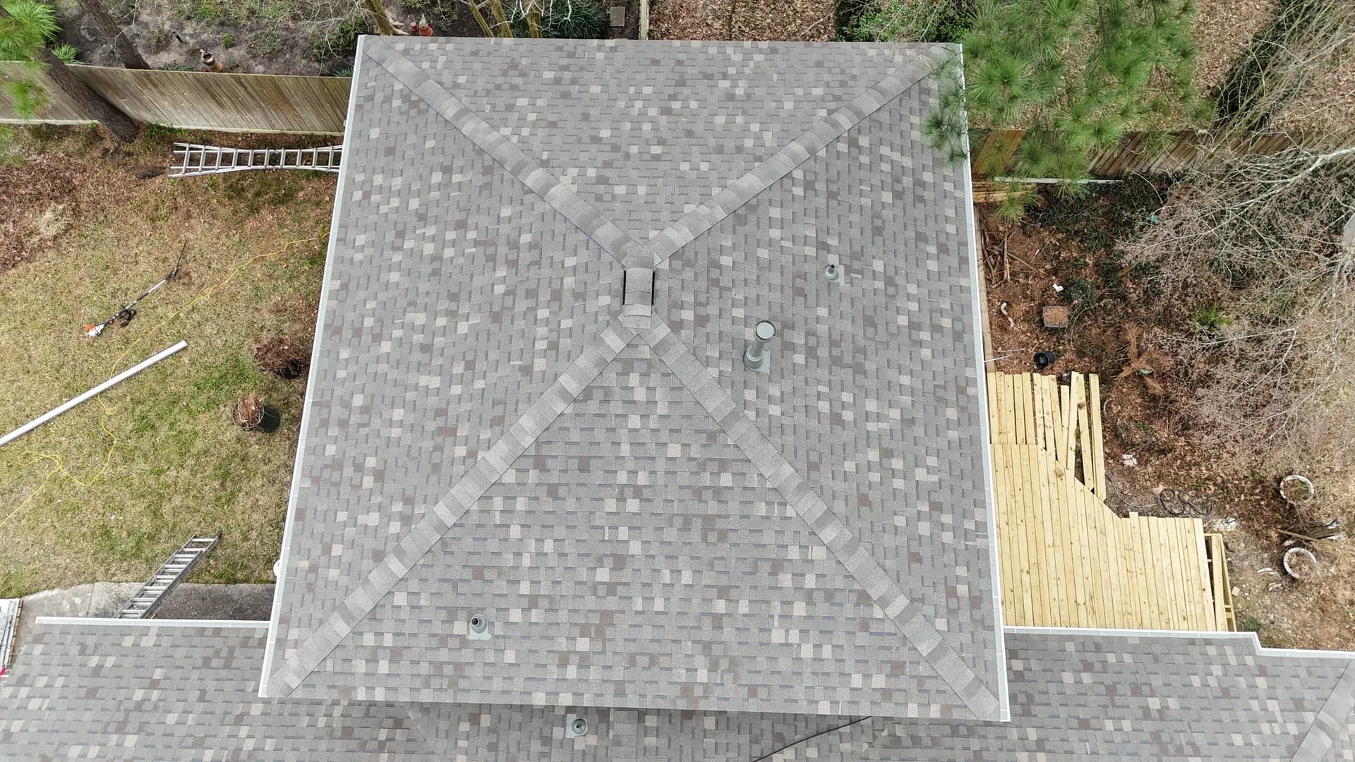 Straight-down aerial of a finished symmetrical hip roof in gray architectural shingles with crisp clean lines