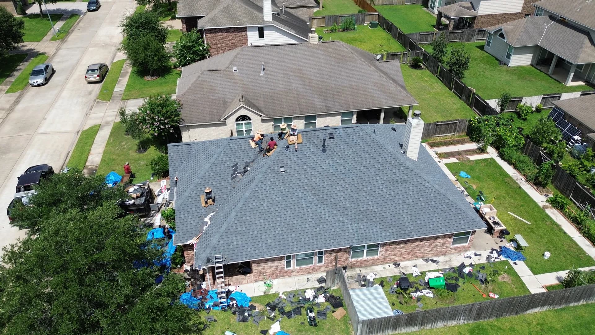 Aerial drone view of a completed gray shingle roof with a valley roofline and a rooftop vent stack