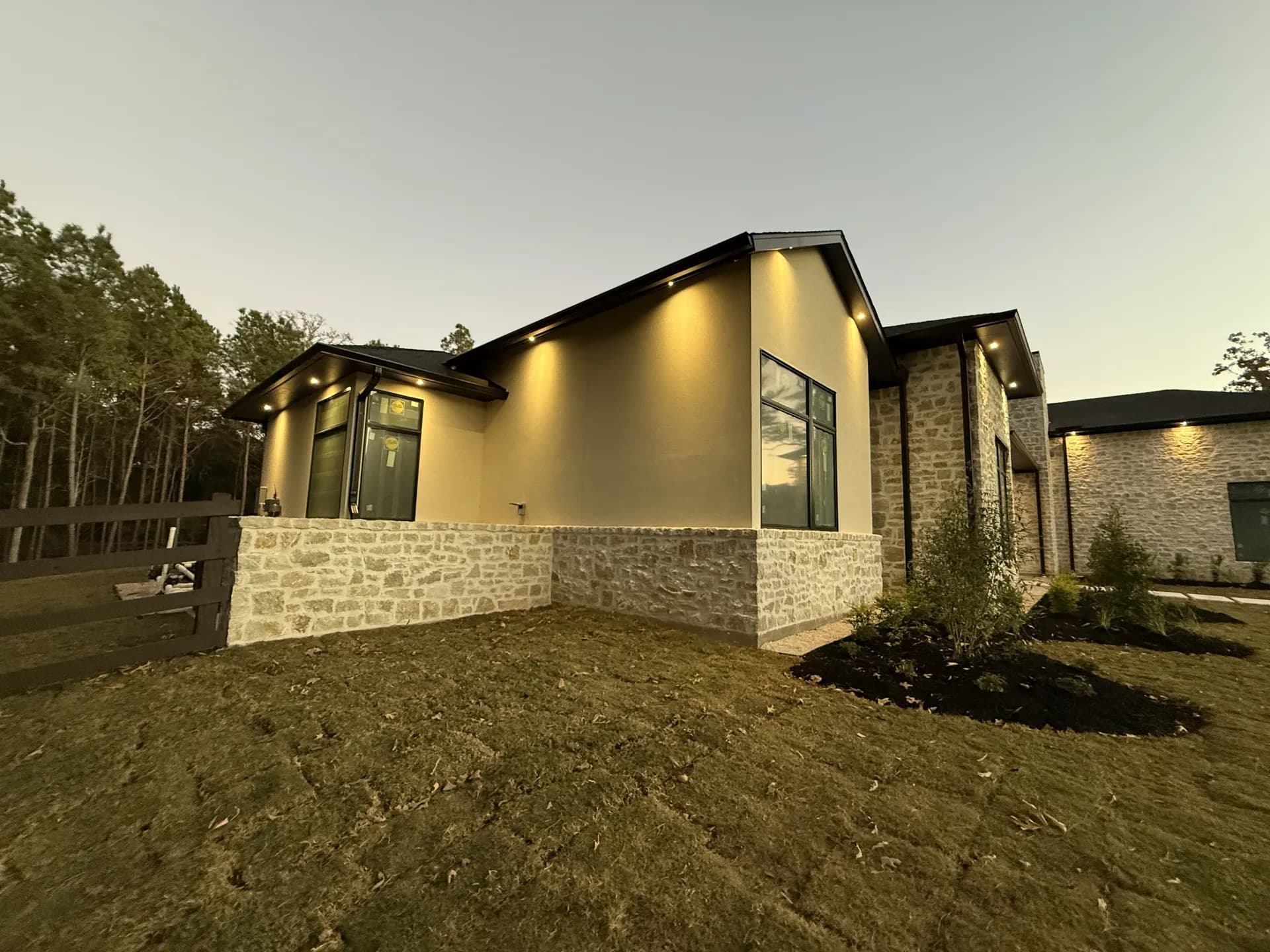 Modern stucco and stone home exterior with a smooth three-coat finish photographed at twilight