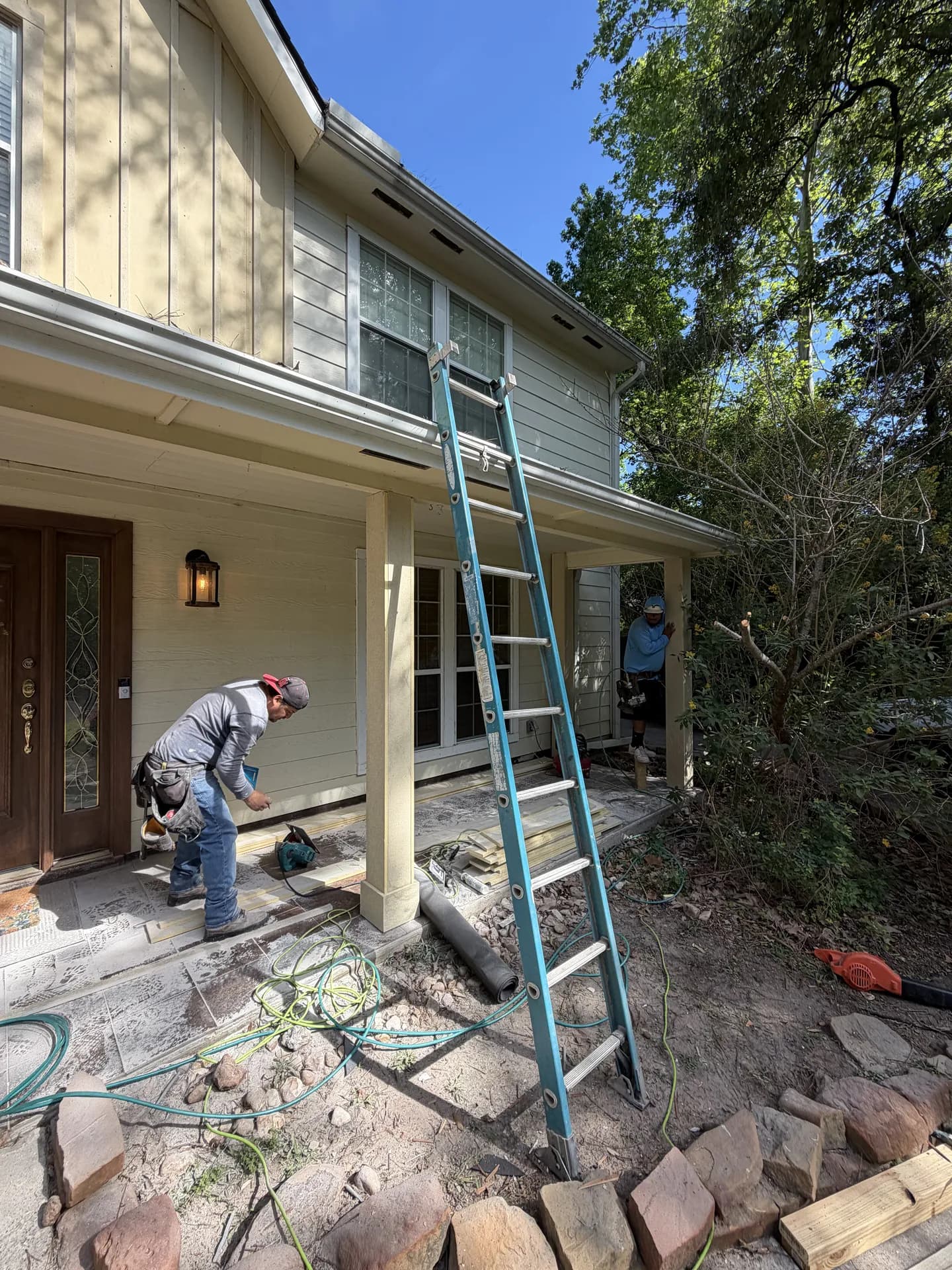 Crew finishing exterior trim at a porch roofline where soffit, fascia, and siding meet